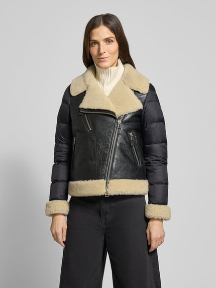 Vrouwenmodel draagt Regular Fit Jack uit echt leer Model 'Candor' van Blauer VS, zwart met beige, reverskraag met imitatiebont, borstzak met ritssluiting, steekzakken met ritssluiting, mouwen met stikpatroon, ruglengte maat M 62 cm, schouderbreedte 38 cm, borstwijdte 48 cm, mouwlengte 65 cm, geheel voorkant zicht.