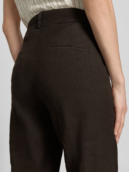 Frauenmodel trägt Chino aus Leinen-Mix mit Bügelfalte Modell 'CALIFORNIA' von Cambio, Gesäßtasche, dunkler Farbton, Nahaufnahme Rückansicht. Damen Chino, Leinen-Mix mit Baumwoll-Anteil, Straight Fit, Haken- und Reißverschluss, Französische Eingrifftaschen, Bundweite bei Größe 36: 41 cm, Innenbeinlänge bei Größe 36: 68 cm.