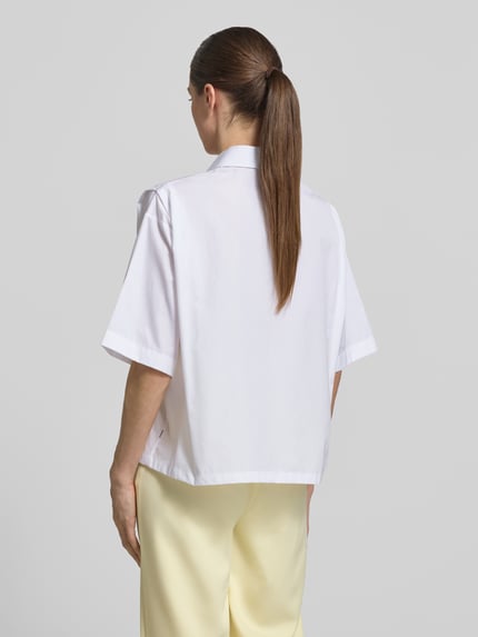 Frauenmodel trägt Oversized Hemdbluse aus reiner Baumwolle Modell 'BIMINA' von BOSS in Weiß, kurze Ärmel, Popeline, Rückansicht Ganzkörperansicht.