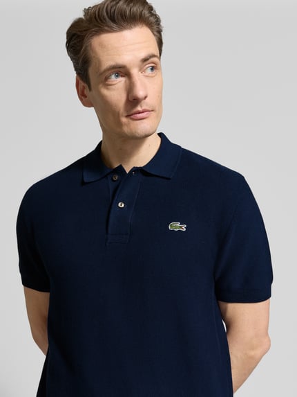 Männermodel trägt Regular Fit Poloshirt aus reiner Baumwolle von Lacoste, Optik: Unifarben, Logo-Stitching, Nahaufnahme Oberkörper.
