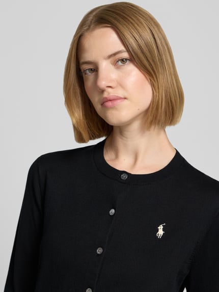 Frauenmodel trägt Slim Fit Strickjacke aus Baumwoll-Mix von Polo Ralph Lauren in Schwarz mit aufgesticktem Logo, Nahaufnahme Oberkörper. Damen Strickjacke von Polo Ralph Lauren.