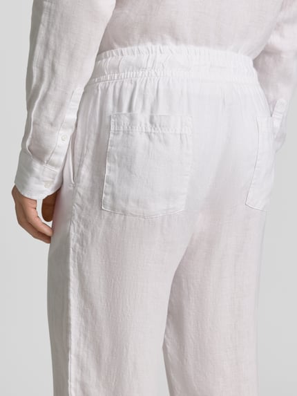 Männermodel trägt Leinenhose mit elastischem Bund von MCNEAL in Weiß, Reines Leinen, Regular-Fit, Tunnelzug, Detailaufnahme Rückenansicht.