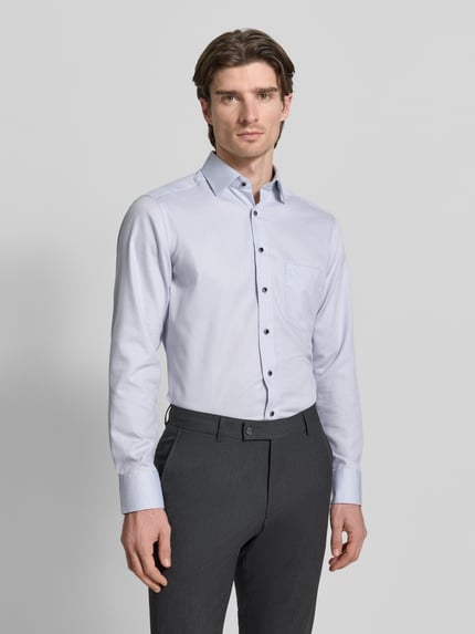 Männermodel trägt Regular Fit Businesshemd aus Baumwolle mit Kentkragen von OLYMP, hellblau, schwarze Knöpfe, Brusttasche, Ganzkörperansicht von vorne.