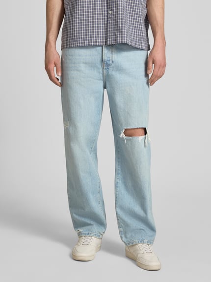 Männermodel trägt Loose Fit Jeans aus reine katoen Modell 'FADE' van Only & Sons, denim look met destroyed-details, 5-pocket design, label patch en knoopsluiting, lichte blauwe kleur, vooraanzicht, detailopname bovenlichaam.