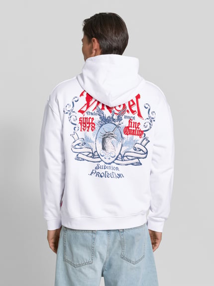Männermodel trägt Oversized Hoodie aus reiner Baumwolle von Diesel in Weiß mit Label-Print und Känguru-Tasche, Rückansicht Ganzkörperansicht.
