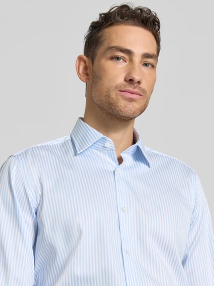 Männermodel trägt Regular Fit Businesshemd mit extra langem Arm Modell 'H-JOE-K' von BOSS, hellblau-weiß gestreift, Nahaufnahme Oberkörper