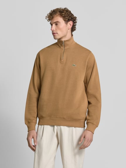 Männermodel trägt Regular Fit Troyer aus reiner Baumwolle von Lacoste in Braun mit Reißverschluss, Herren Troyer von Lacoste, Ganzkörperansicht von vorne.