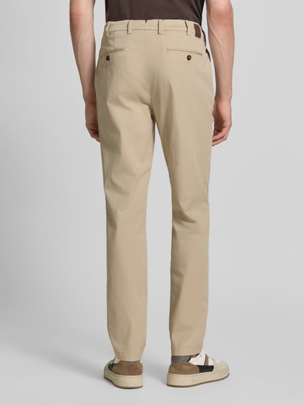 Männermodel trägt Slim Fit Hose mit Eingrifftaschen Modell 'Tybalt 5' von g1920, beiges Baumwoll-Mix, glatte Oberfläche, Ganzkörperansicht Rückansicht.