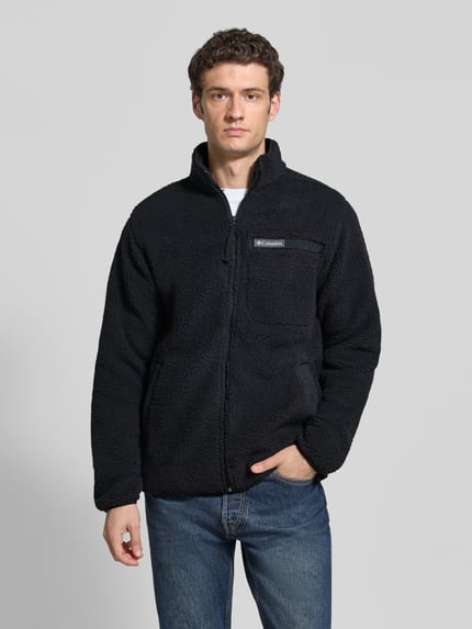 Männermodel trägt Regular Fit Fleecejacke mit Logo-Patch von Columbia, schwarze Struktur, Brusttasche, Langarm, Ganzkörperansicht von vorne.