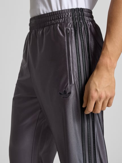 Männermodel draagt Jogpants met labelstitching model 'FIREBIRD' van adidas Originals, regular fit, elastische band, detailopname heup.