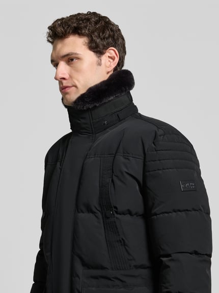 Männermodel trägt Heren parka met capuchon van NAUTGÅRD 'J-LHOTSE 226', effen kleuren, labeldetail, sierzakken, deelnaad, lang, ritssluiting, drukknopen, klepzakken, ritszakken, binnenzak, lange mouw, elastisch, rompzoom met tunnelkoord, detailopname bovenlichaam