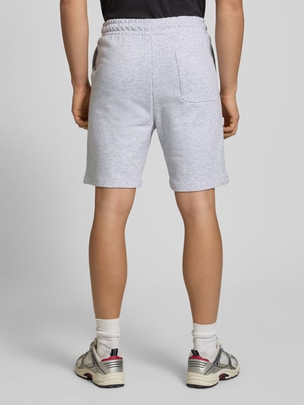 Männermodel trägt Sweatshorts mit Logo Model 'KANE' von Jack & Jones aus Baumwoll-Mix in Grau, Relaxed-Fit, Ganzkörperansicht Rückansicht.