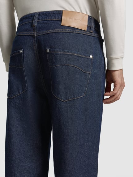 Männermodel trägt Regular Fit Jeans mit Label-Patch von RETERNITY in Raw Denim mit Kontrastnähten, Ganzkörperansicht Rückansicht.