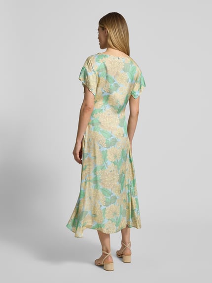 Vrouwenmodel draagt Midikleid uit viscose met bindegürtel van Rich & Royal in lichtgroen met bloemenprint, getailleerd model, boothals, ruglengte maat 36: 123 cm, borstwijdte: 50 cm, mouwlengte: 9 cm, geheelopname rugaanzicht.