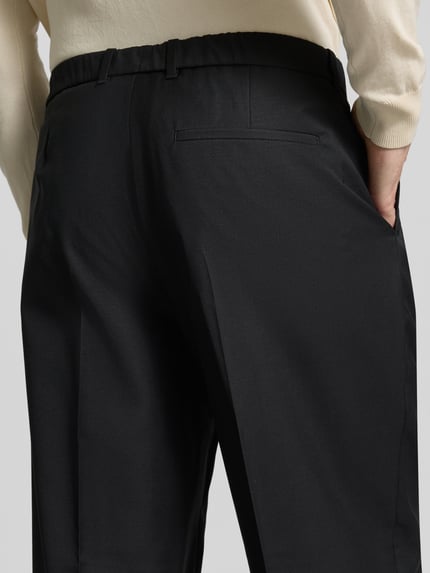 Männermodel trägt schwarze Hose aus Woll-Mix mit weitem Bein und Gesäßtasche von CK Calvin Klein, Nahaufnahme Rückansicht.