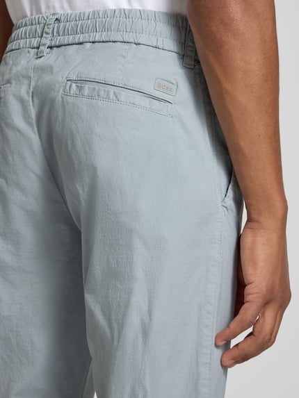 Mannenmodel draagt lichtblauwe tapered fit chino uit katoenmix model 'GABARDINE' van BOSS Orange, detailopname billen.