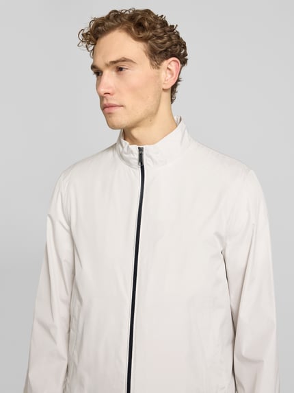 Männermodel trägt blouson mit opstaande kraag en ritssluiting van Geox, regular fit, steekzakken, licht beige, nahaufnahme bovenlichaam.