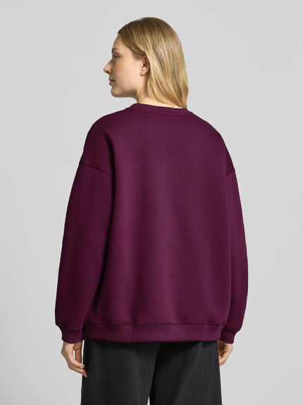 Modelka nosi Oversized Sweatshirt aus Baumwoll-Mix mit Statement-Stickerei von Smith and Soul, mieszanka bawełny, głęboki fiolet, prążkowane wykończenia, okrągły dekolt, krój oversized, widok całej sylwetki od tyłu.