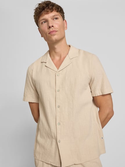 Männermodel trägt Resort Fit Freizeithemd aus reiner Baumwolle von s.Oliver RED LABEL in Beige mit weicher Struktur, Ganzkörperansicht von vorne.
