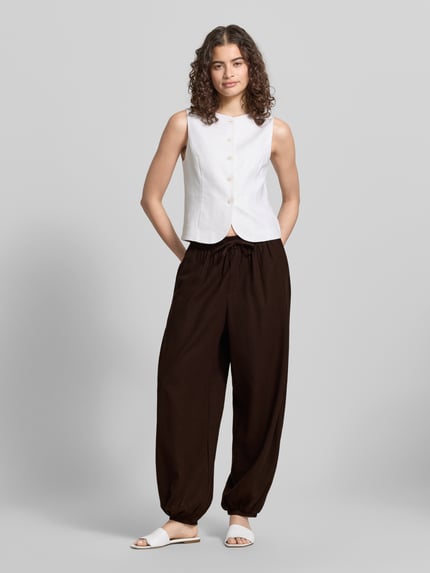 Frauenmodel trägt Regular Fit Weite Hose aus Viskose-Leinen-Mix Modell 'GOA' von Only in Optik: Unifarben mit Tunnelzug, Bundabschluss: elastisch, Beinabschluss: elastisch, seitliche Eingrifftaschen, Gesäßtasche, Materialverarbeitung: Flammgarn, Ganzkörperansicht von vorne.