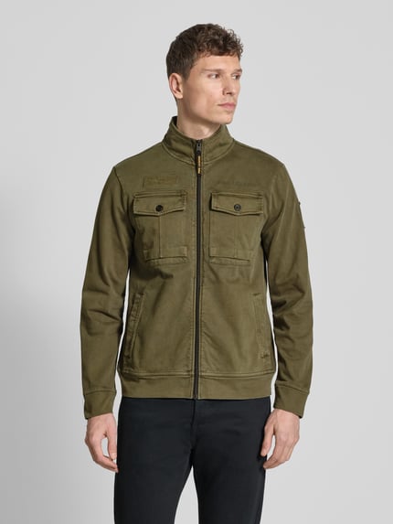 Mannelijk model draagt Jacke mit Stehkragen und Brusttaschen van PME Legend in olijfgroen, puur katoen, regular fit, opstaande kraag, ritssluiting, borstzakken, ruglengte maat M 67 cm, schouderbreedte 46 cm, borstwijdte 58 cm, mouwlengte 65 cm. Ganzkörperansicht van voren.