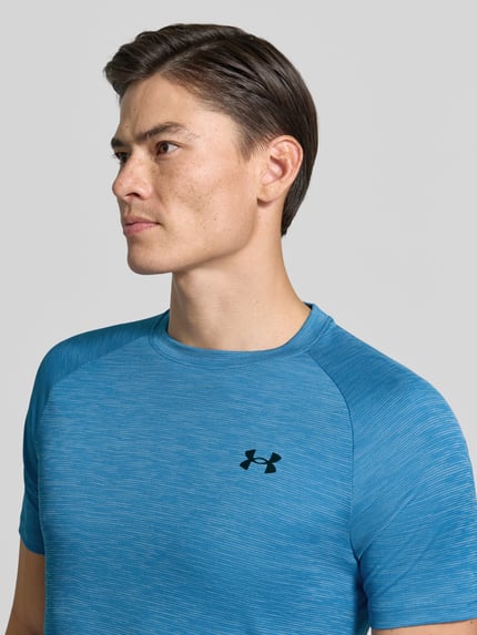 Männermodel trägt Regular Fit Sport-T-Shirt mit Logo-Print von Under Armour in Blau, feine Struktur, Nahaufnahme Oberkörper, Herren Sport-T-Shirt von Under Armour