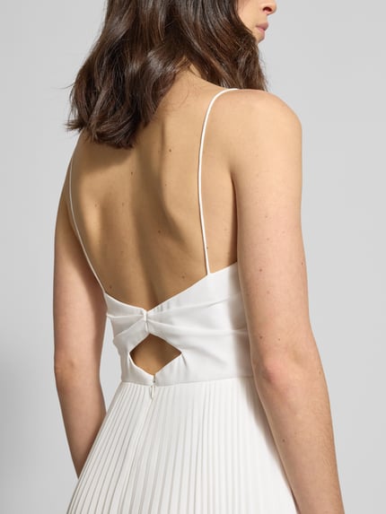 Frauenmodel trägt Regular Fit Hochzeitskleid in Falten-Optik von Hey Kyla, cremeweiß, Rückenausschnitt, Nahtreißverschluss, Spaghettiträger, Gelegte Falten, Rückenlänge 127 cm, Brustweite 33 cm, Nahaufnahme Rückenansicht.