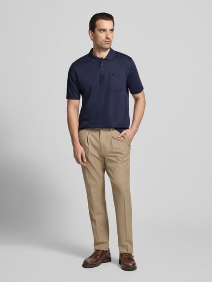 Männermodel trägt Regular Fit Poloshirt mit Brusttasche von Christian Berg Men in Dunkelblau, Material-Mix mit Baumwoll-Anteil, Polokragen, Knopfleiste, Herren, Ganzkörperansicht von vorne.
