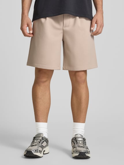 Männermodel trägt Loose Fit Shorts mit elastischem Bund Modell 'WILL' von Only & Sons, unifarben, Bundfalte, Nahaufnahme Oberschenkel