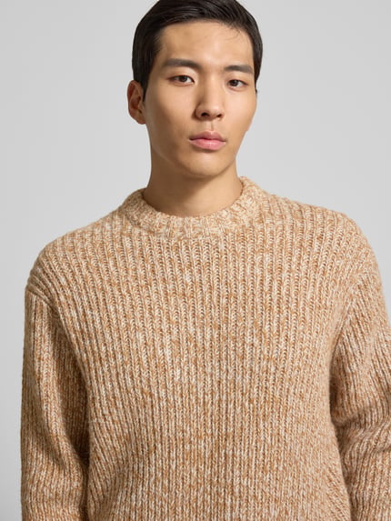 Männermodel trägt Relaxed Fit Wollpullover mit überschnittenen Schultern Modell 'CHICAGO' von SELECTED HOMME in Melange-Optik, Grobstrick, Woll-Mix, Rundhals, Nahaufnahme Oberkörper.
