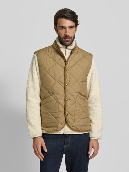Männermodel trägt Weste mit Stehkragen von Polo Ralph Lauren in Beige mit Druckknopfleiste und Eingrifftaschen, Ganzkörperansicht von vorne.