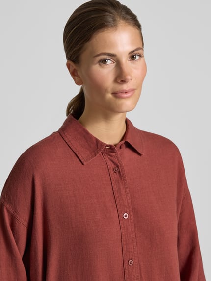 Vrouwenmodel draagt linnen blouse met overhemdkraag model 'SALINAS' van Mustang, mix van viscose en linnen, loose fit, knoopsluiting, structuurstof, detailopname bovenlichaam.