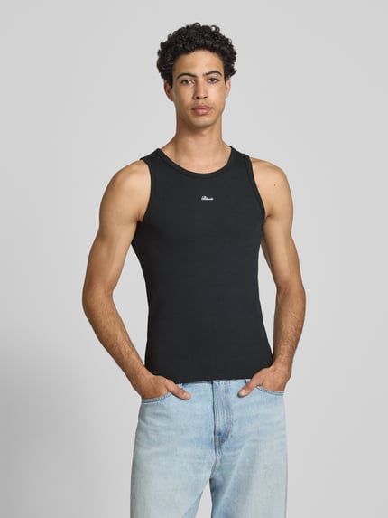 Męski model nosi Tanktop in Ripp-Optik mit Label-Stitching von BLKVIS, mieszanka bawełny i elastanu, krój slim fit, efekt prążkowania, wyhaftowane logo, długość tyłu w rozmiarze M: 63 cm, całkowity widok z przodu.