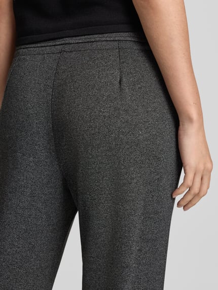 Frauenmodel trägt Jogpants in Two-Tone-Machart mit Tunnelzug von Christian Berg Woman, Material-Mix mit Viskose-Anteil, Nahaufnahme Rückansicht.