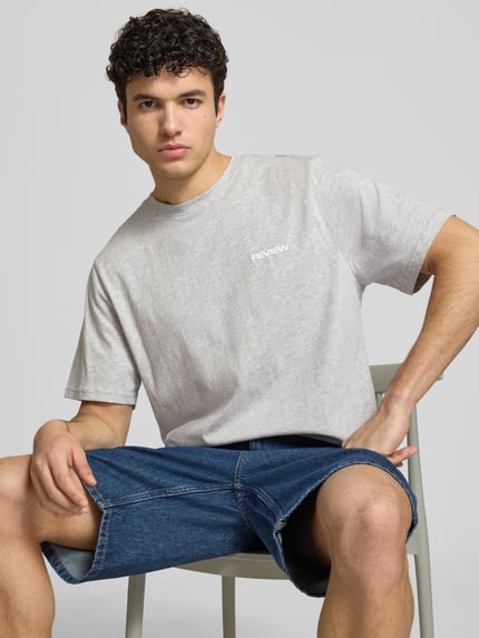 Männermodel trägt T-shirt mit Logo und ronde hals van REVIEW, katoen- en viscosemix, regular fit, ruglengte maat M 64 cm, Nahaufnahme Oberkörper