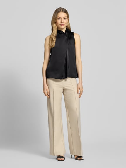 Modelka nosi Regular Fit Blusentop in Wickel-Look Modell 'CHELINA-1' od HUGO, czarny satynowy top bez rękawów, mock neck, krój regular fit, widok całej sylwetki z przodu.