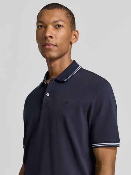 Männermodel trägt Slim Fit Poloshirt mit Label-Stitching von bugatti aus reiner Baumwolle, dunkelblau, Nahaufnahme Oberkörper.