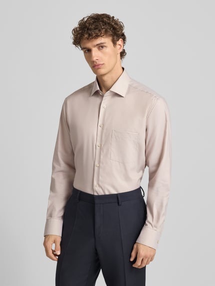 Männermodel trägt Regular Fit Businesshemd aus Baumwolle mit Kentkragen von Eterna, beige, Knopfleiste, Brusttasche, Ganzkörperansicht von vorne. Rückenlänge bei Größe 40: 80 cm, Schulterbreite: 49 cm, Ärmellänge: 65 cm.