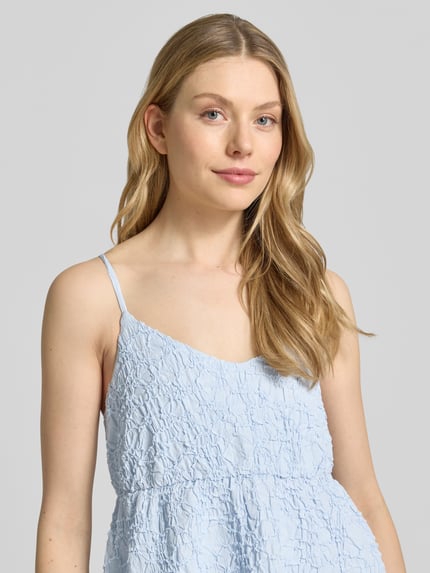 Frauenmodel trägt Midikleid mit Strukturmuster Modell 'CRISTINA' von Copenhagen Muse in Hellblau, A-Linie, Nahaufnahme Oberkörper.