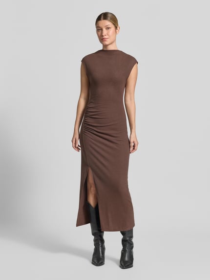 Frauenmodel trägt Maxikleid mit Raffungen Modell 'BASILA' von MANGO in Braun, figurbetonter Schnitt, Seitenschlitz, Material-Mix, Ganzkörperansicht von vorne.