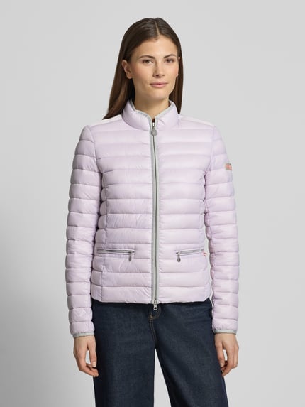 Frauenmodel trägt Steppjacke mit Reißverschlusstaschen Modell 'SISTER JUDY' von Frieda & Freddies in Helllila, Ganzkörperansicht von vorne, Slim Fit, Stehkragen, glatte Struktur, Damen Steppjacke Kontext.