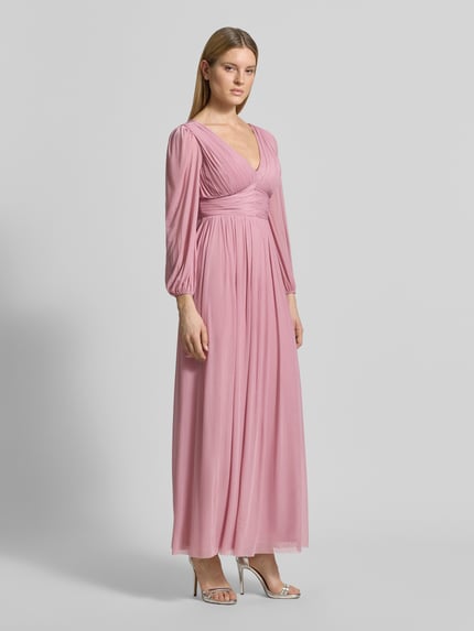 Vrouwenmodel draagt Regular Fit avondjurk in plooien-look van Lipsy in roze met V-hals, elastische materiaalmix, met lange mouwen, getailleerd, onderrok, ruglengte maat 36: 135 cm, borstwijdte: 45 cm, mouwlengte: 62 cm, volledige lichaamsaanzicht vooraan.