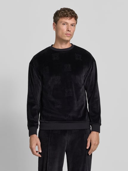 Männermodel trägt Sweatshirt mit Samtstruktur von HUGO mit Allover-Muster, Rundhals, gerippten Abschlüssen, Struktur-Optik, Ganzkörperansicht von vorne.