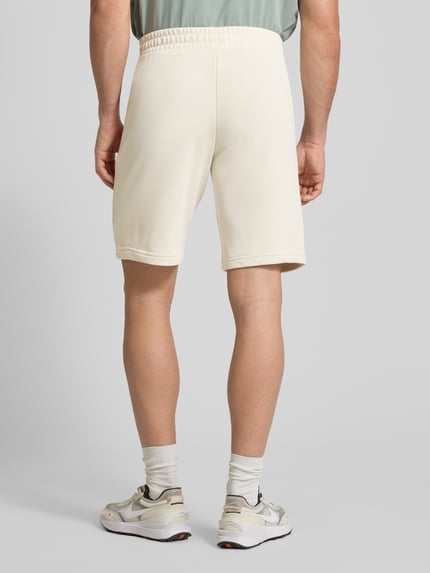 Männermodel trägt Shorts mit Label-Stitching von PUMA PERFORMANCE in Beige, elastischer Bund, Baumwoll-Mix, Ganzkörperansicht Rückansicht.