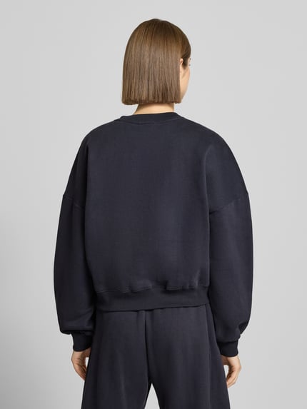 Frauenmodel trägt Sweatshirt mit Label-Print und Rundhalsausschnitt von Review aus Baumwoll-Mix im Relaxed-Fit, dunkler Farbton, Ganzkörperansicht Rückansicht.
