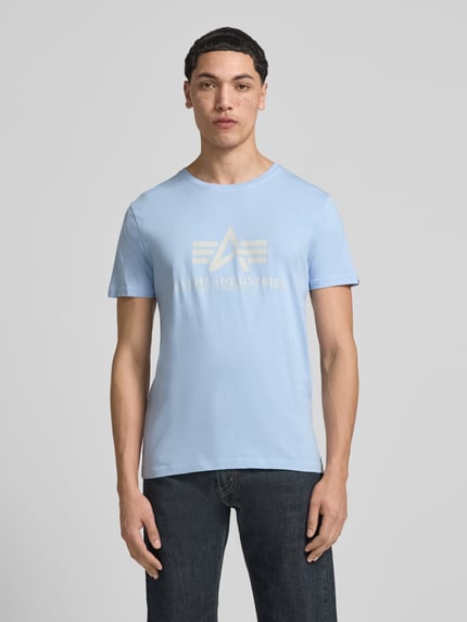 Männermodel trägt Herren T-Shirt mit Label-Detail Modell 'BASIC' von Alpha Industries in Hellblau, Reine Baumwolle, Gerader-Schnitt, Rundhalsausschnitt, Rückenlänge bei Größe M 69 cm, Ganzkörperansicht von vorne.