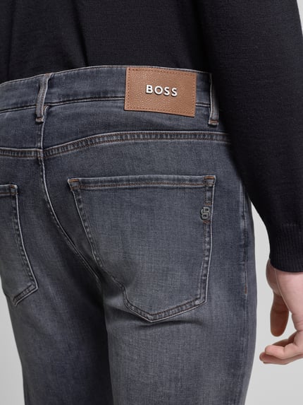 Mężczyznamodel nosi Slim Fit Jeans aus Baumwoll-Mix Modell 'DELAWARE' od BOSS, kolor szary denim, naszywka z logo, nity, 5 kieszeni, mieszanka bawełny, detal z metalu, widok tylu z bliska.