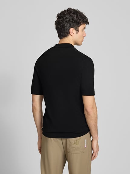 Męski model nosi Regular Fit Poloshirt aus Viskose-Mix Modell 'WYLER' od Only & Sons, czarny, gładki, krótki rękaw, krój regular fit, tekstura drobno dzianinowa, widoczne logo naszywka, kołnierzyk polo, zamknięcie na krótki zamek, perspektywa: całe ciało z tyłu.
