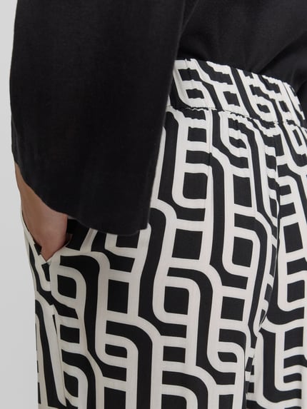 Vrouwenmodel draagt Wide Leg Pants uit viscose met steekzakken van Christian Berg Woman, zwart-wit grafisch patroon, detailopname heup.