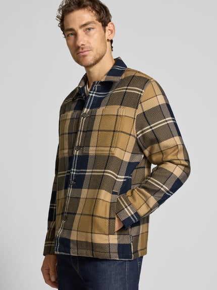 Männermodel trägt Hemdjacke aus reiner Baumwolle Modell 'OVERSHIRT' von Barbour, kariertes Muster, Knöpfe, Brusttasche, Ganzkörperansicht von vorne.